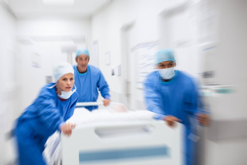 Promisecare Medical Group - A group of surgeons swiftly transporting a patient in a hospital bed to the Urgent Care.