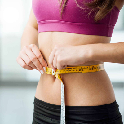 Promisecare Medical Group - A woman participating in a FREE Health Education program, measuring her waist with a measuring tape.