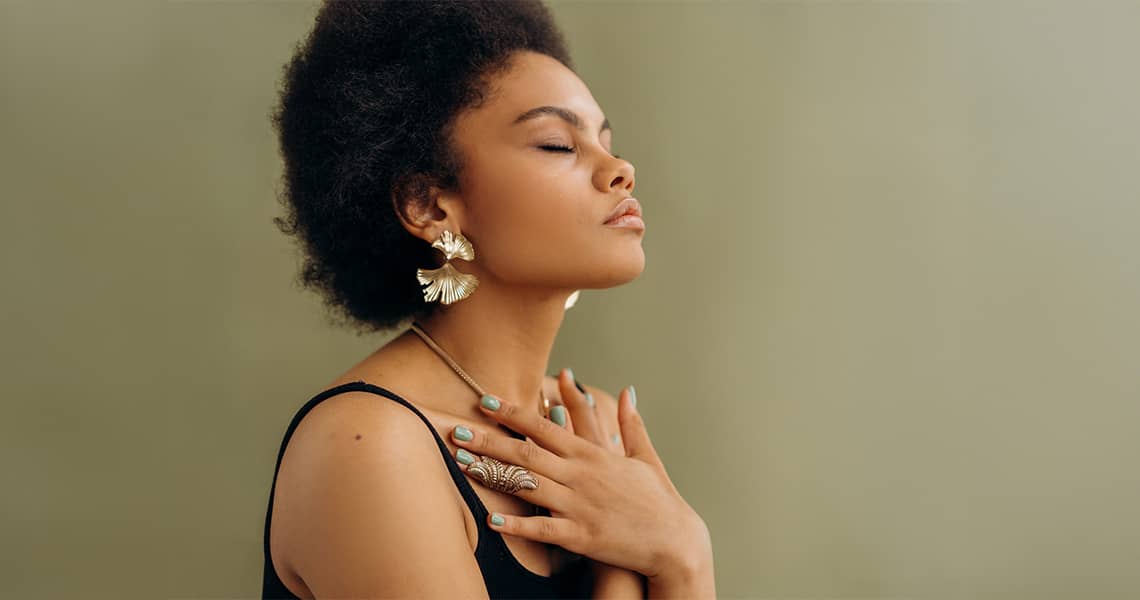Promisecare Medical Group - A woman with an afro with her hands on her chest.