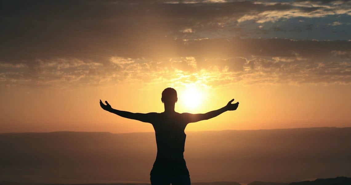 Promisecare Medical Group - A silhouette of a man with his arms outstretched at sunset.
