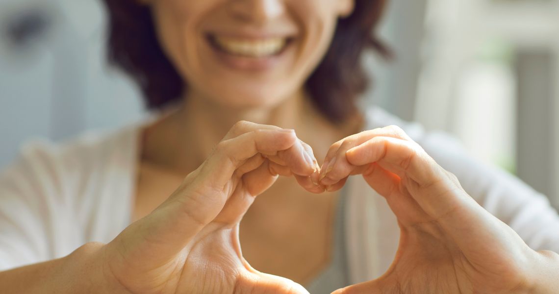 Promisecare Medical Group - A woman is making a heart shape with her hands.