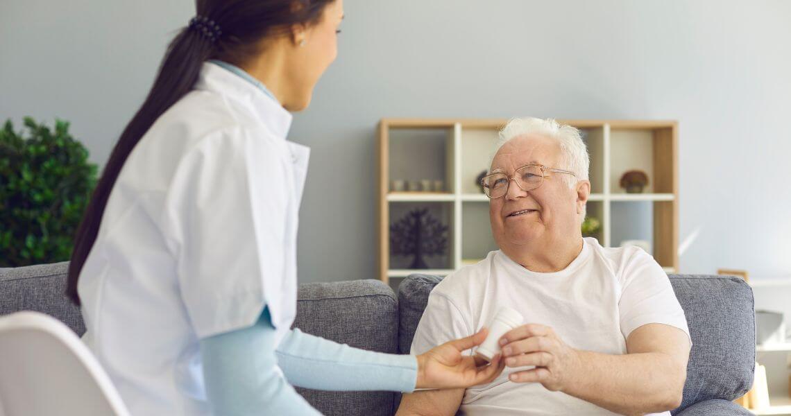 Promisecare Medical Group - A nurse is helping an elderly man on the couch.