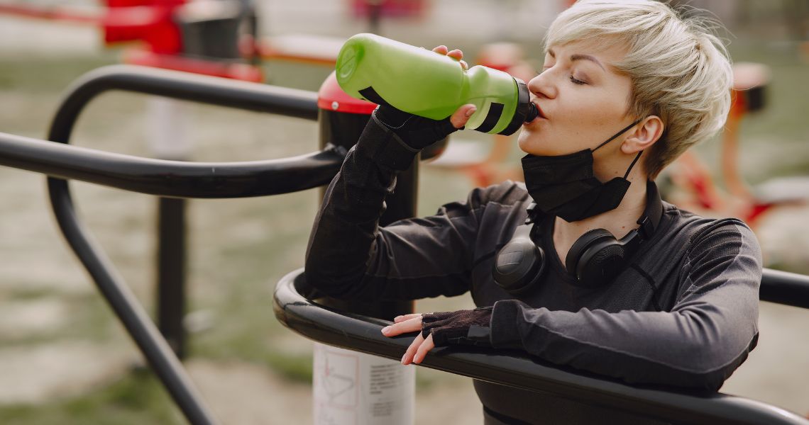 Promisecare Medical Group - A woman drinking from a water bottle in a park.