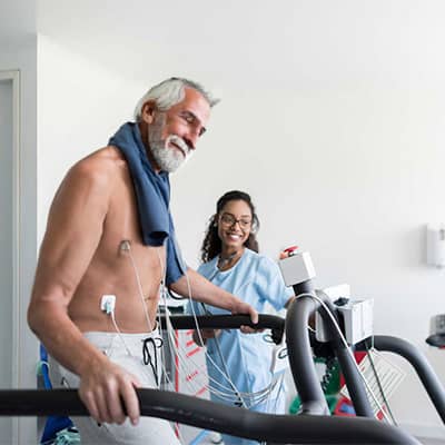 Promisecare Medical Group - An older man and a nurse participating in a FREE Annual Wellness Physical on a treadmill.