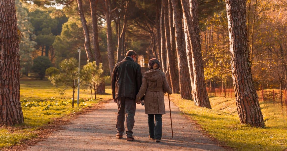 Promisecare Medical Group - A couple walking down a path in the woods.