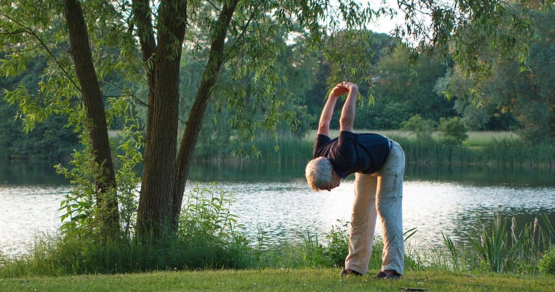 Promisecare Medical Group - A woman doing yoga in a park near a lake.