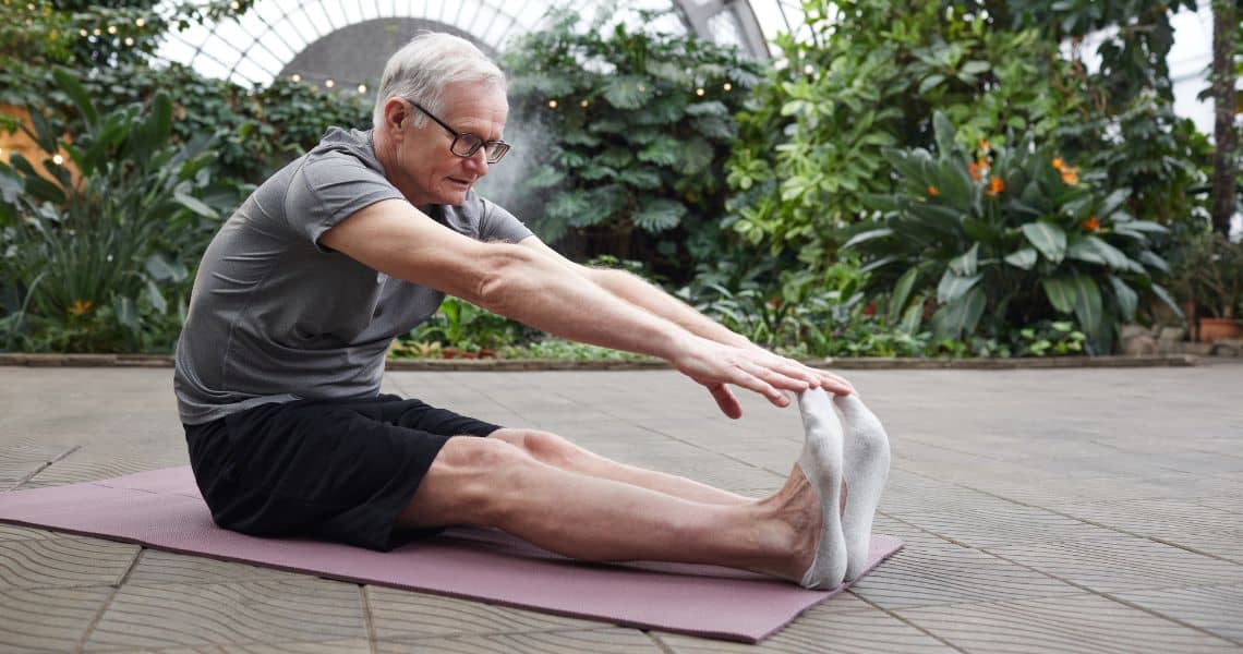 Promisecare Medical Group - An older man doing a yoga exercise in a garden.