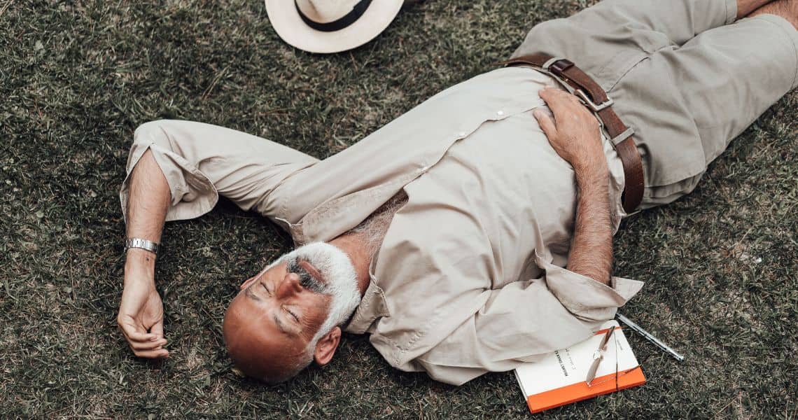 Promisecare Medical Group - A man lying on the grass with a hat on.