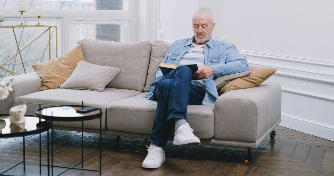 Promisecare Medical Group - A man sitting on a couch reading a book.
