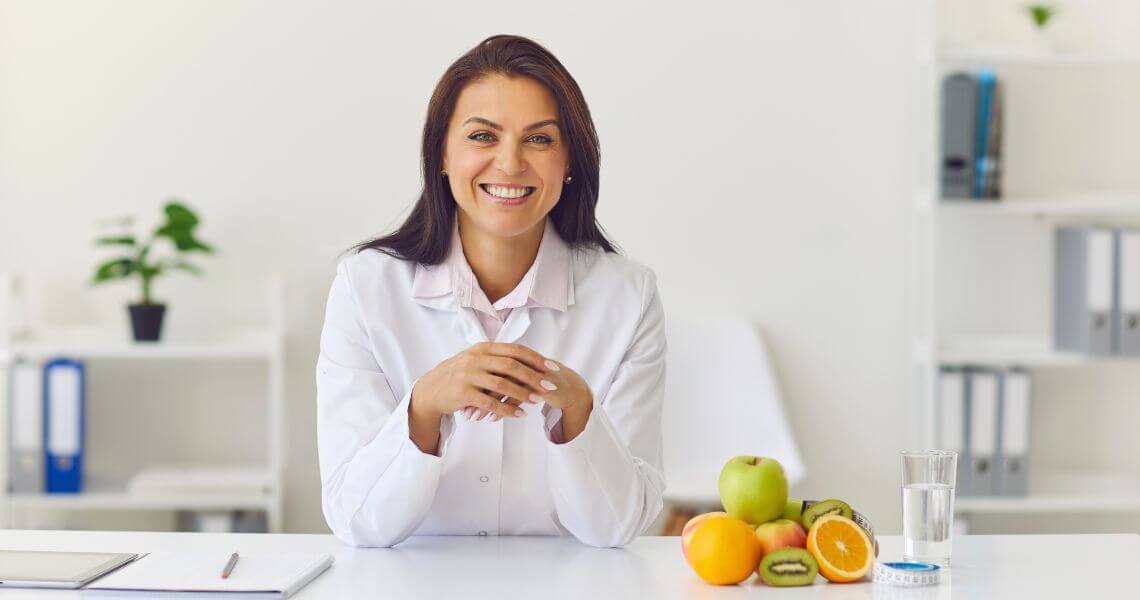 Promisecare Medical Group - A female doctor sitting at a desk with fruit.