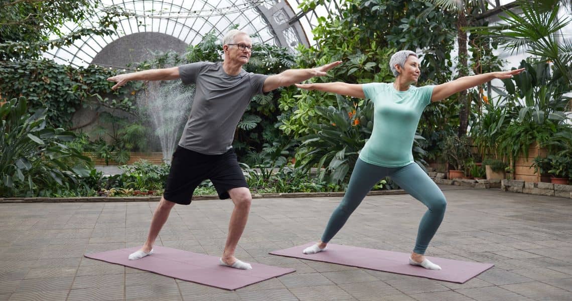 Promisecare Medical Group - Two people doing yoga in a greenhouse.