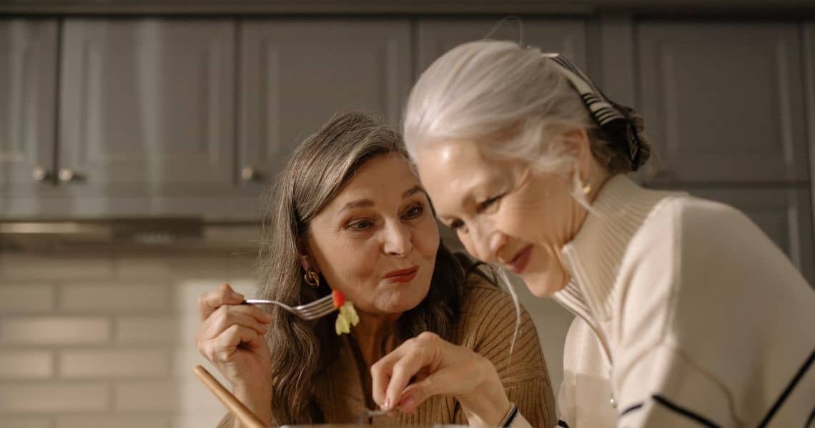Promisecare Medical Group - Two older women are eating together in a kitchen.