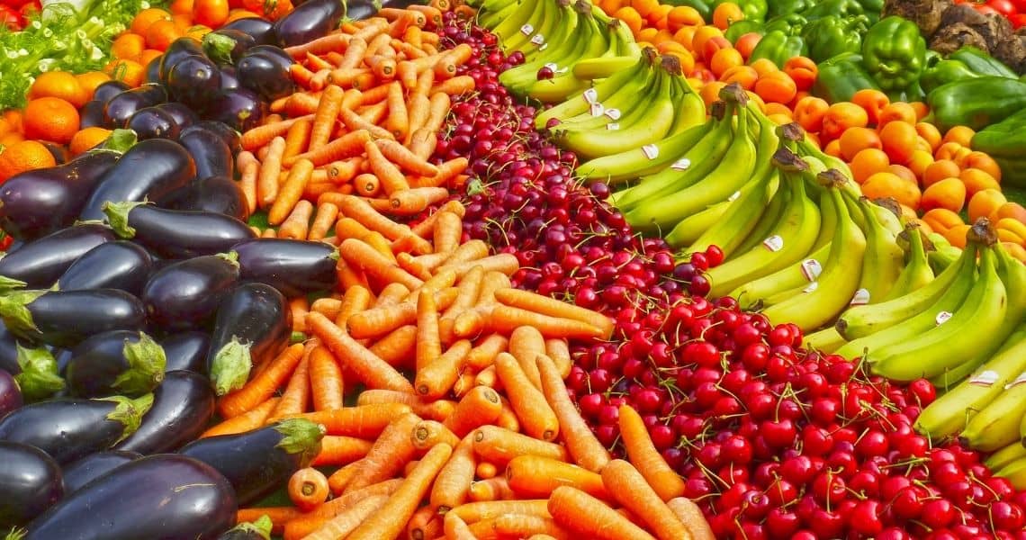 Promisecare Medical Group - An array of fresh produce including bananas, oranges, carrots, eggplants, and cherries arranged at a market.