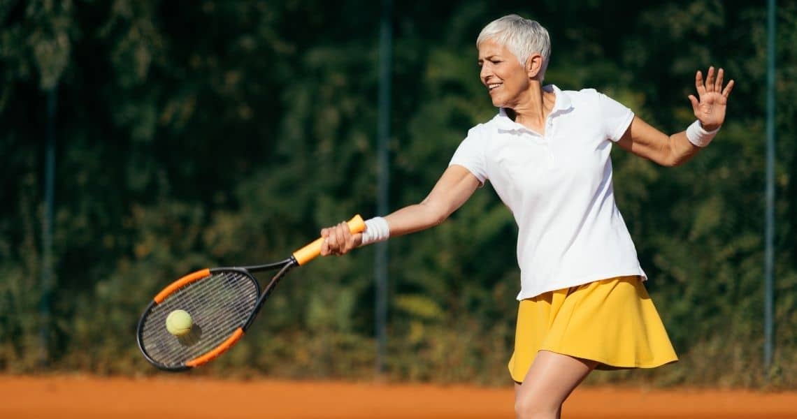 Promisecare Medical Group - A woman with short hair rejuvenates her routine by playing tennis on a clay court.