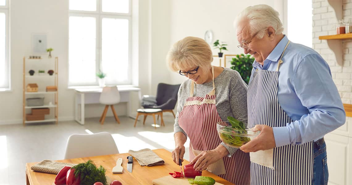 Promisecare Medical Group - Senior couple preparing a meal together in a bright kitchen.
