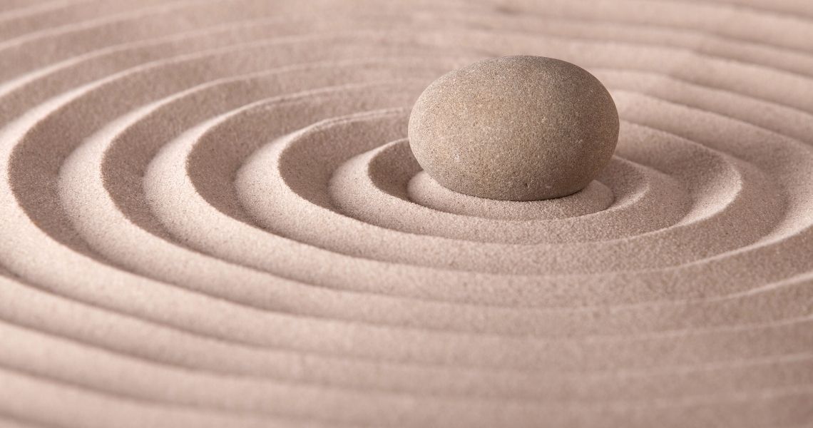 Promisecare Medical Group - A single smooth stone centered in the concentric circles of a sand zen garden.